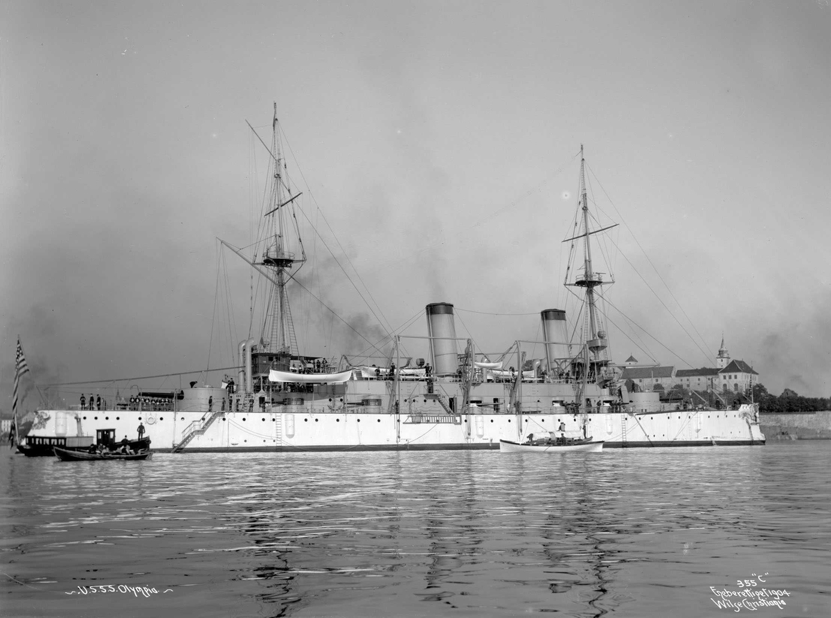 Anders Beer Wilse, U.S.S. Olympia (b. 1892, Union Iron Works, San Francisco), bredside med Akershus