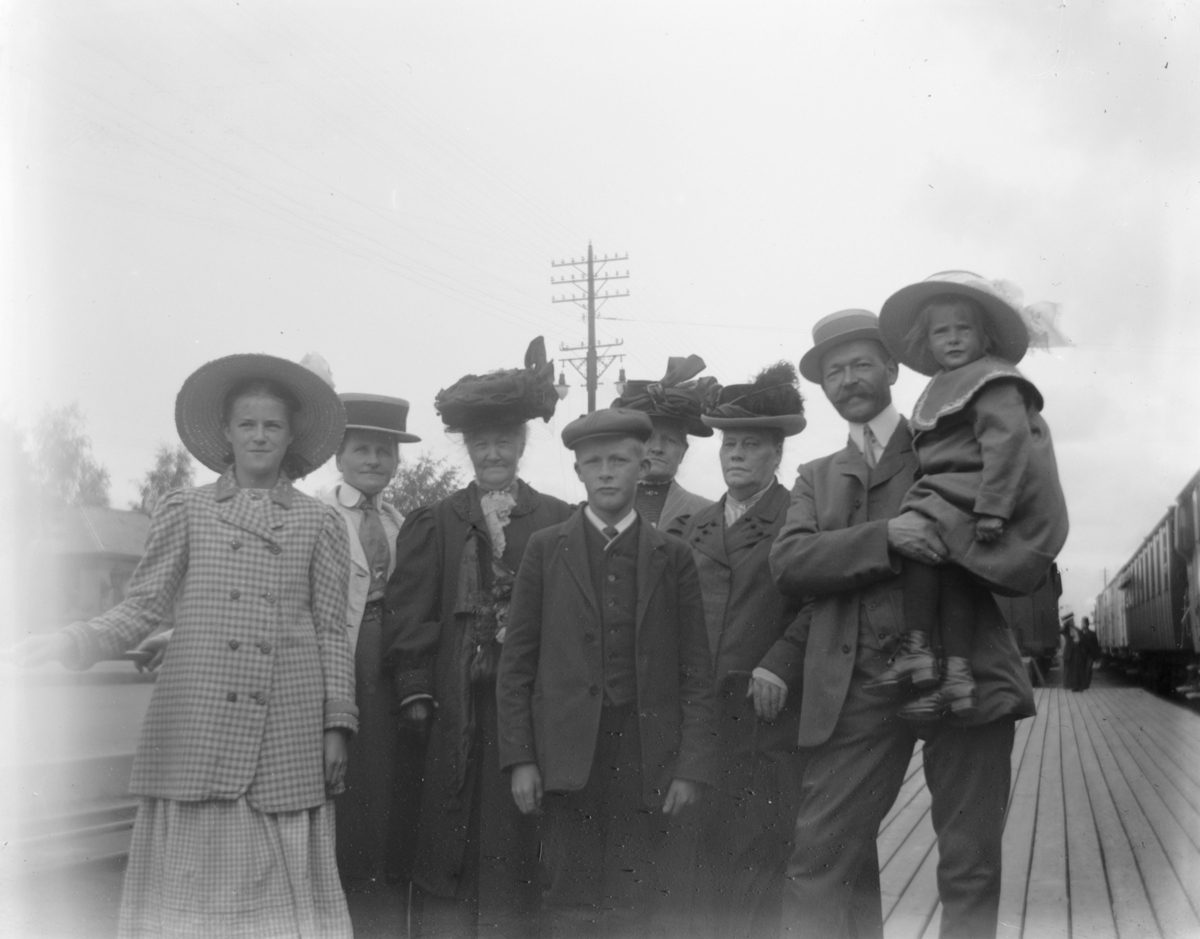 Johs. (Johannes) Johannessen, Familiegruppe på perrongen Hamar Jernbanestasjon, f.v. ukjent, Lovise Johannessen, Botilla Morbech, ukjent, ukjent , ukjent, Johs Johannessen (?), Lumi Johannessen (?), klesdrakter, kvinnedrakter, hatter.