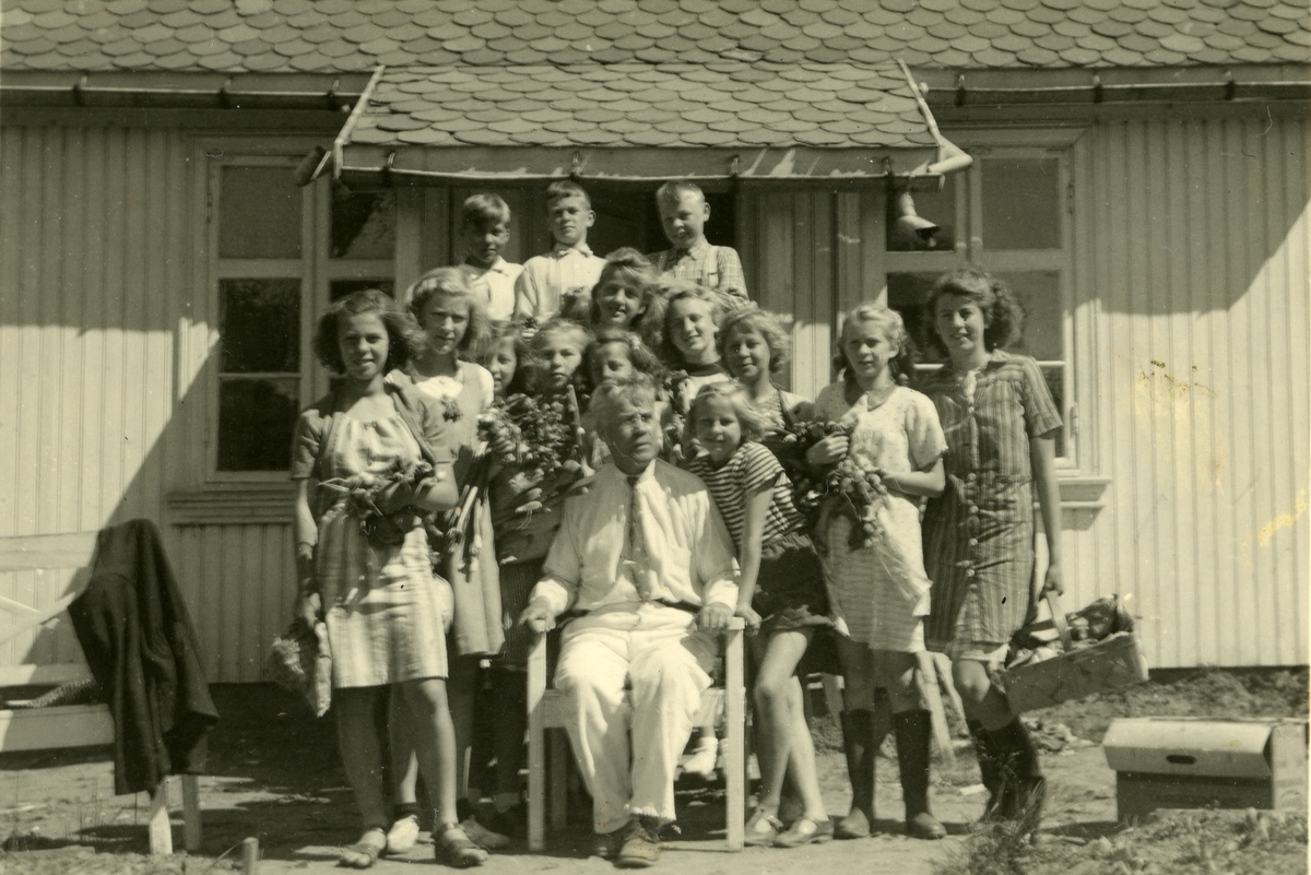 Haakon Garaasen, Skoleklasse i Gjøvik skolehage, Gjøvik. Læreren, Ole Haugen Flermoen (1878 - 1956) sitter i midten. Elevene står rundt ham foran inngangspartiet til skolestua.