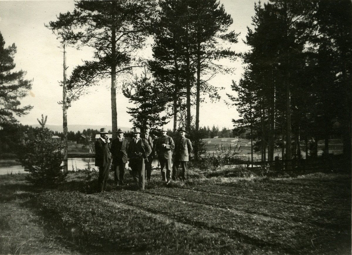 Haakon Garaasen, Gruppe menn stående ved åker/plantefelt i Ljørdalen. Vann/elv i bakgrunnen. Adolfsnes planteskole