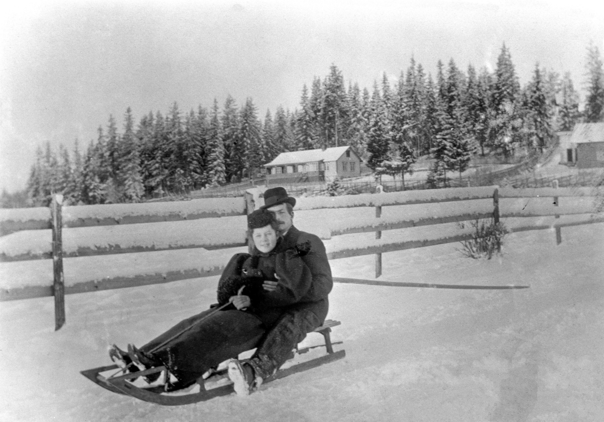 Anno Domkirkeodden, Ingeborg Petersen (datter av overlærer K. Petersen) og vennen Erling på skikjelke i Stafsbergveien, Hamar. Langs skigarden i bakgrunnen går i dag Ringgata. Vinter.