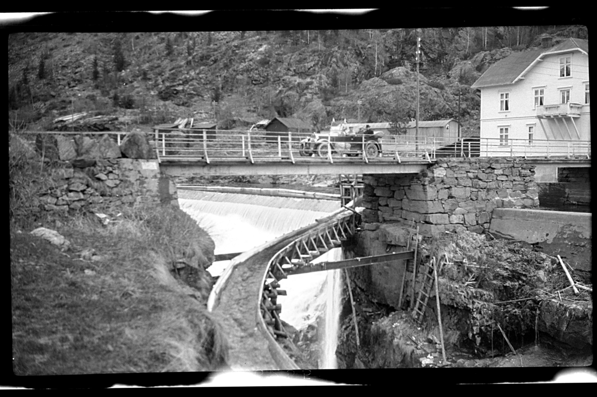 Rolf Sr. Sundt, En bli står på broen, en tømmerrenne blir ført ut fra en foss under en broen. Fotografert 1926.