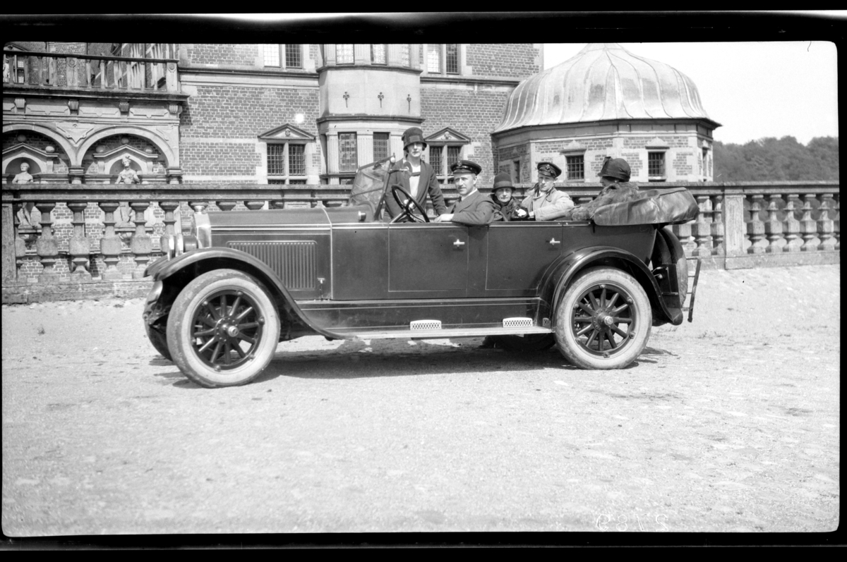 Rolf Sr. Sundt, Hilda Sundt, Rolf Sundt sr., Rebekka Sundt, Peter Ingvard Sundt og Sigrid Sundt sitter i Rolf Sundt sr.'s Buick foran en flott bygning i en ukjent by. Fotografert 1927.