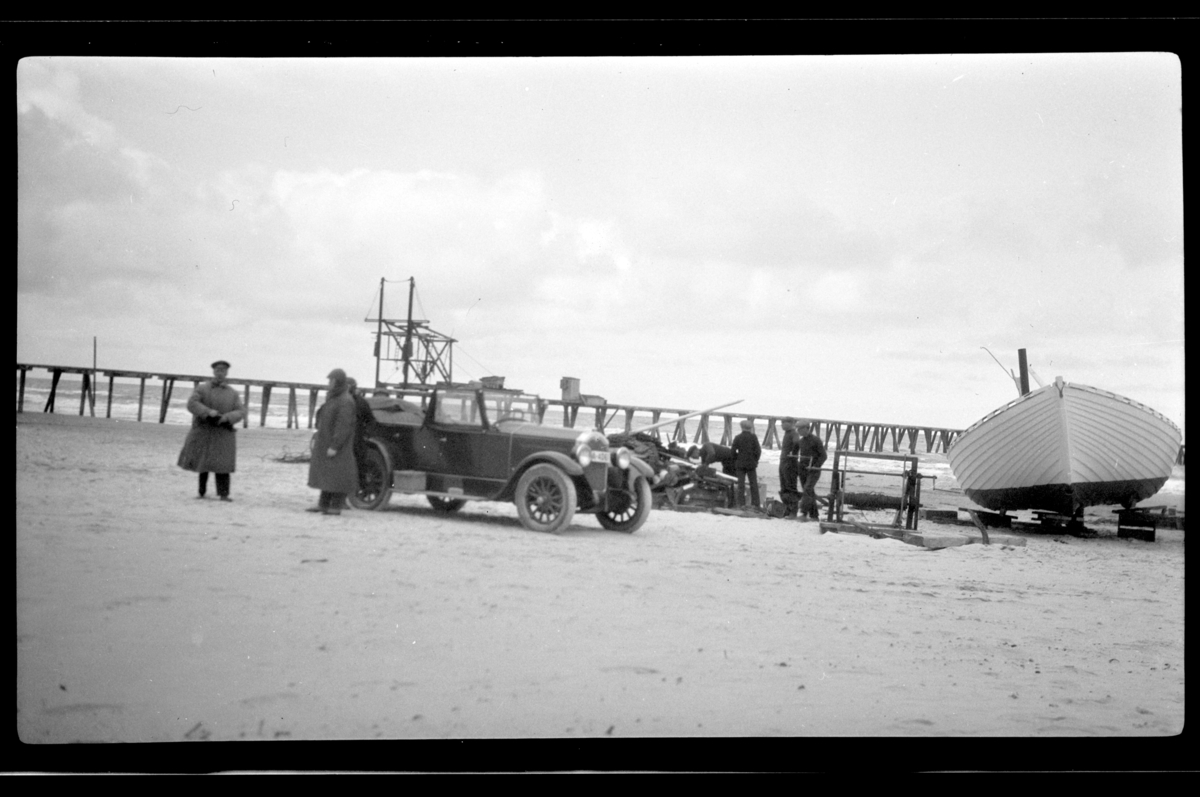 Rolf Sr. Sundt, Til venstre står Rolf Sundt sr. ved siden av Buicken sammen med flere ukjente mennesker, i bakgrunn ligger en båt på standen i Skagen. Fotografert 1927.