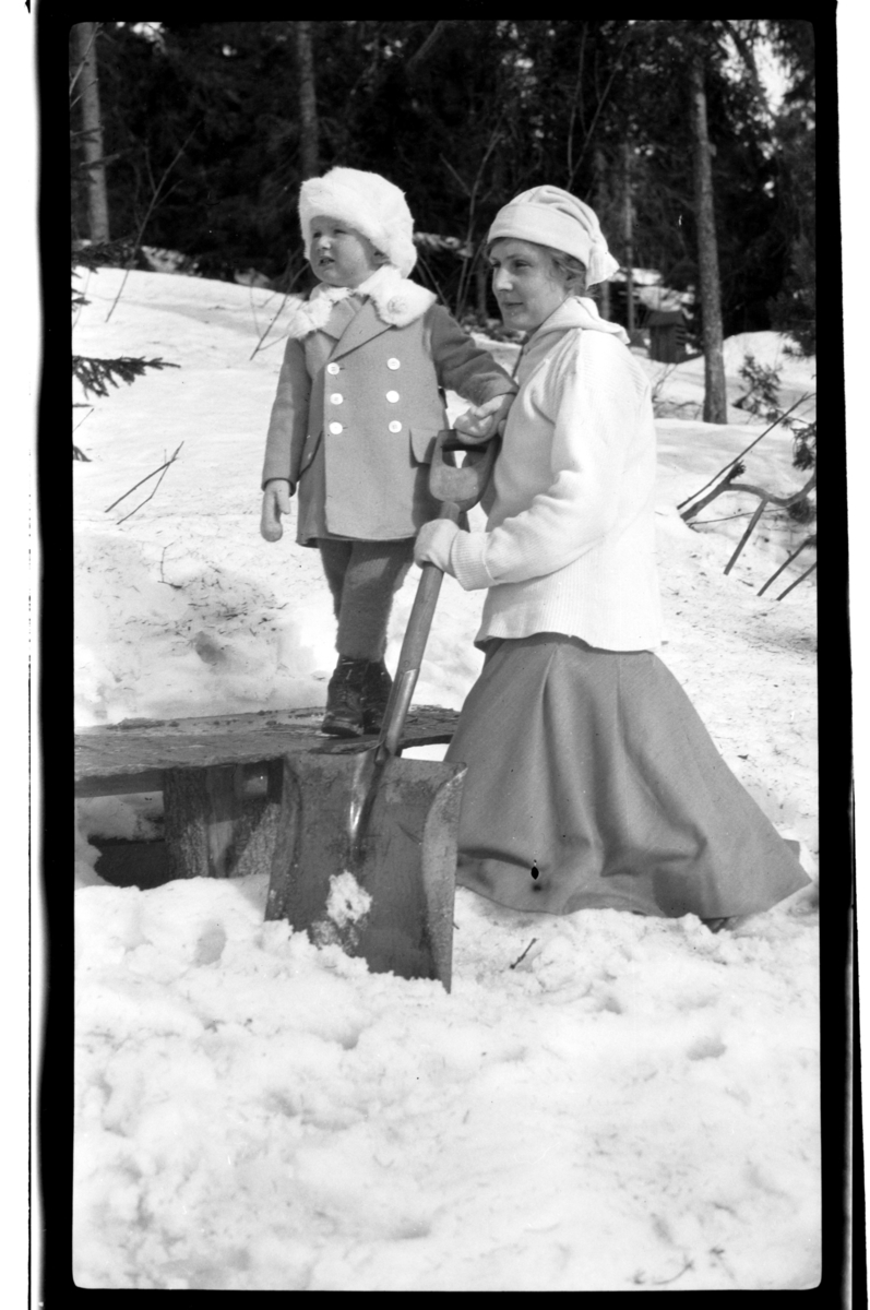 Rolf Sr. Sundt, Hilda Sundt med sin sønn Julius ved en benk med spade i snøen, Villa Knyggen. Fotografert 1918-1919.