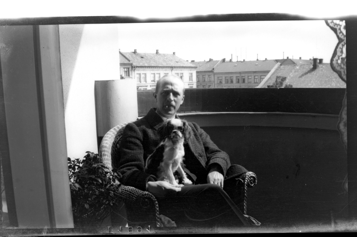 Rolf Sr. Sundt, Rolf Sundt sr. sitter på verandaen med en hund i fanget, Frederiks Stangs gate. Fotografert 1918.