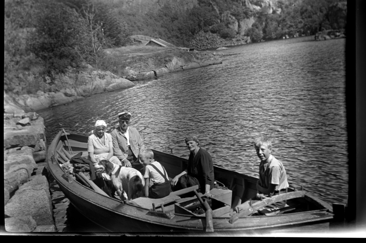 Rolf Sr. Sundt, Ekteparat Agnes og Rolf sr. Sundt. og deres hund Uncas og husholderske Berta Venge sitter sammen med brødrene Odd og Petter Wilhelmsen i en robåt på tur til Spinnanger. Fotografert 2. august 1953.