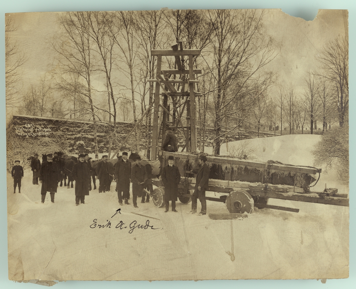 Anders Beer Wilse, Henrik Ibsens gravmonument (obelisk) transporteres til kirkegården. Eirik A. Gude sammen med arbeidere.