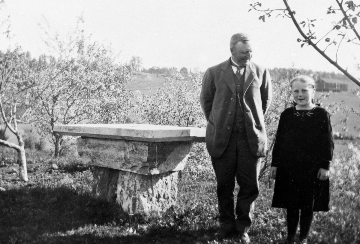 Anno Domkirkeodden, Simen Borud (1873-1962) med datteren Aagot (1911-1993) ved det gamle alterbordet av stein fra den gamle kirken på Baldishol østre. Det er plassert omtrent der det stod inne i kirken. Ca. 1920.