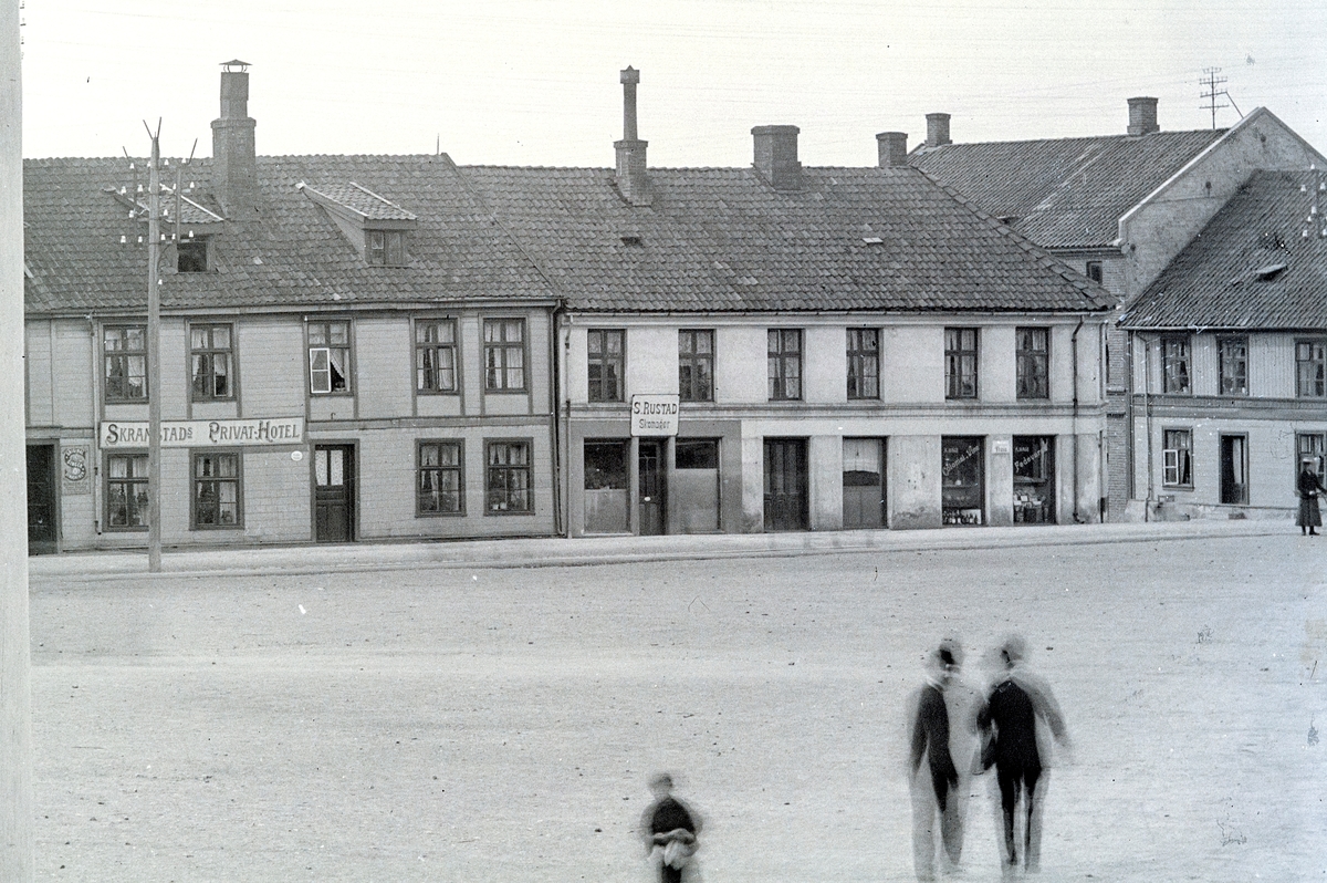 Hans Emil Erichsen, Østre Torg i Hamar. Bebyggelse langs Torggata. Skramstad Privathotell, Skomaker S. Rustad. A. Hage Colonial, Vine og fødevarer. Voksne og barn på torget. Utsnitt.
