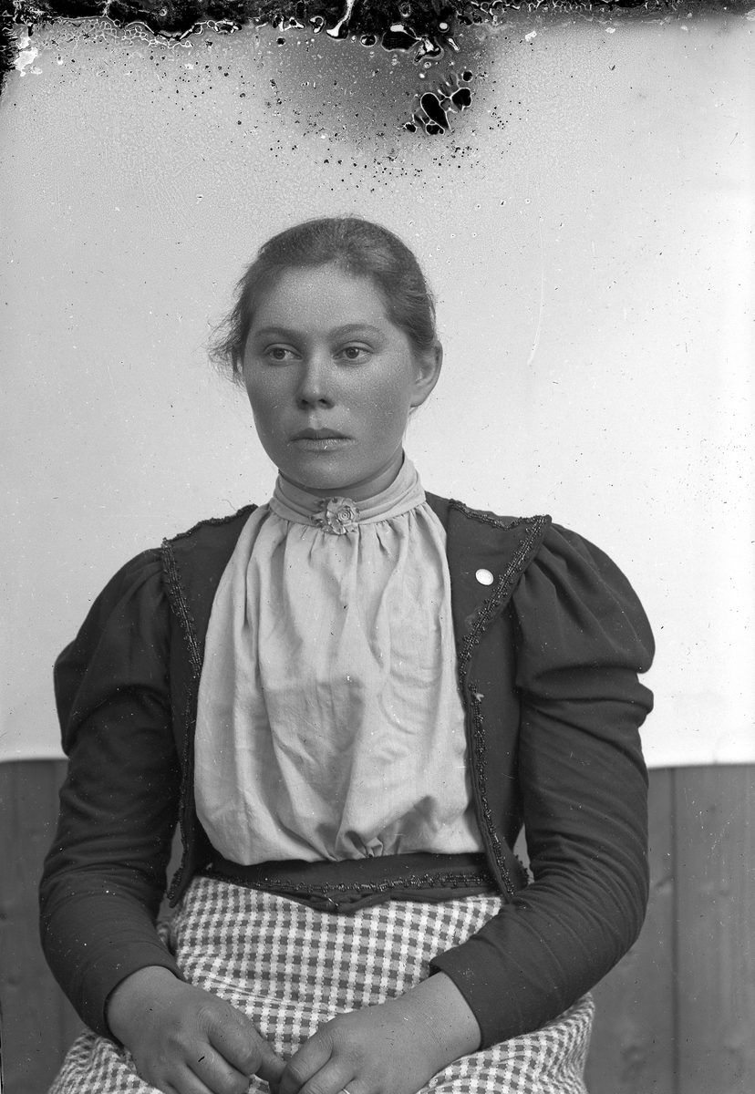 Jakob Jakobsen Engerdal, Portrett av kvinne med lys bluse, mørk jakke og rutet skjørt, sitter.