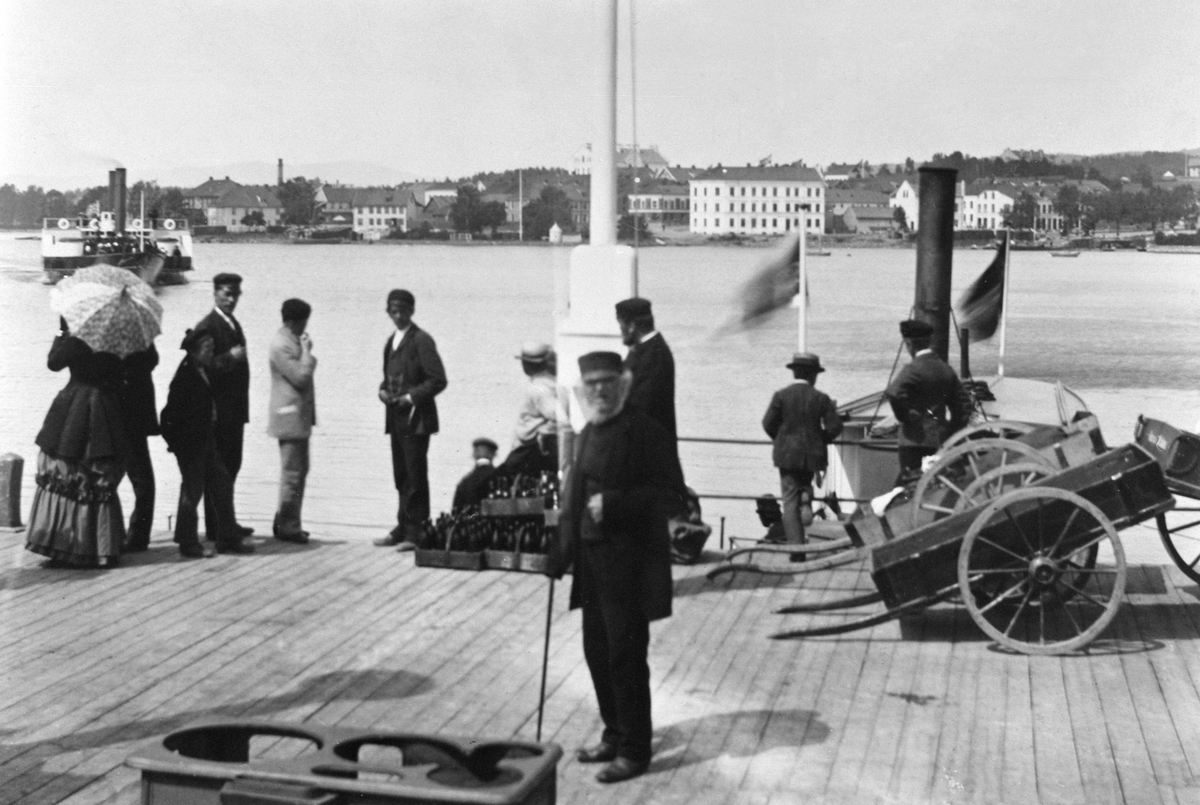 Anno Domkirkeodden, D. S. Skibladner på vei ut fra brygga, D. S. Lettvindt til høyre, mjøsbåter ved Jernbanebrygga, mye folk, varer, kjerre.