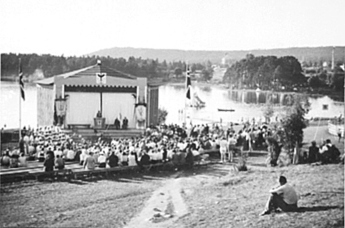 Anno Domkirkeodden, DOMKIRKEODDEN OG HEDMARKSMUSEET, UTESCENE, ROSENLUNDSVIKA, TALER MED TILHØRERE, MYE FOLK, BÅTER PÅ MJØSA I BAKGRUNNEN.