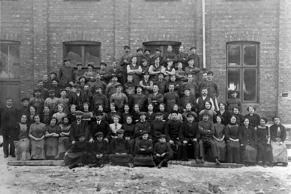 Anno Domkirkeodden, Norrøna skofabrikk, Hamar. Arbeidsstokken 1922. Mann med skalk disponent Bakke. Bak ham sitter Anna Tømte.