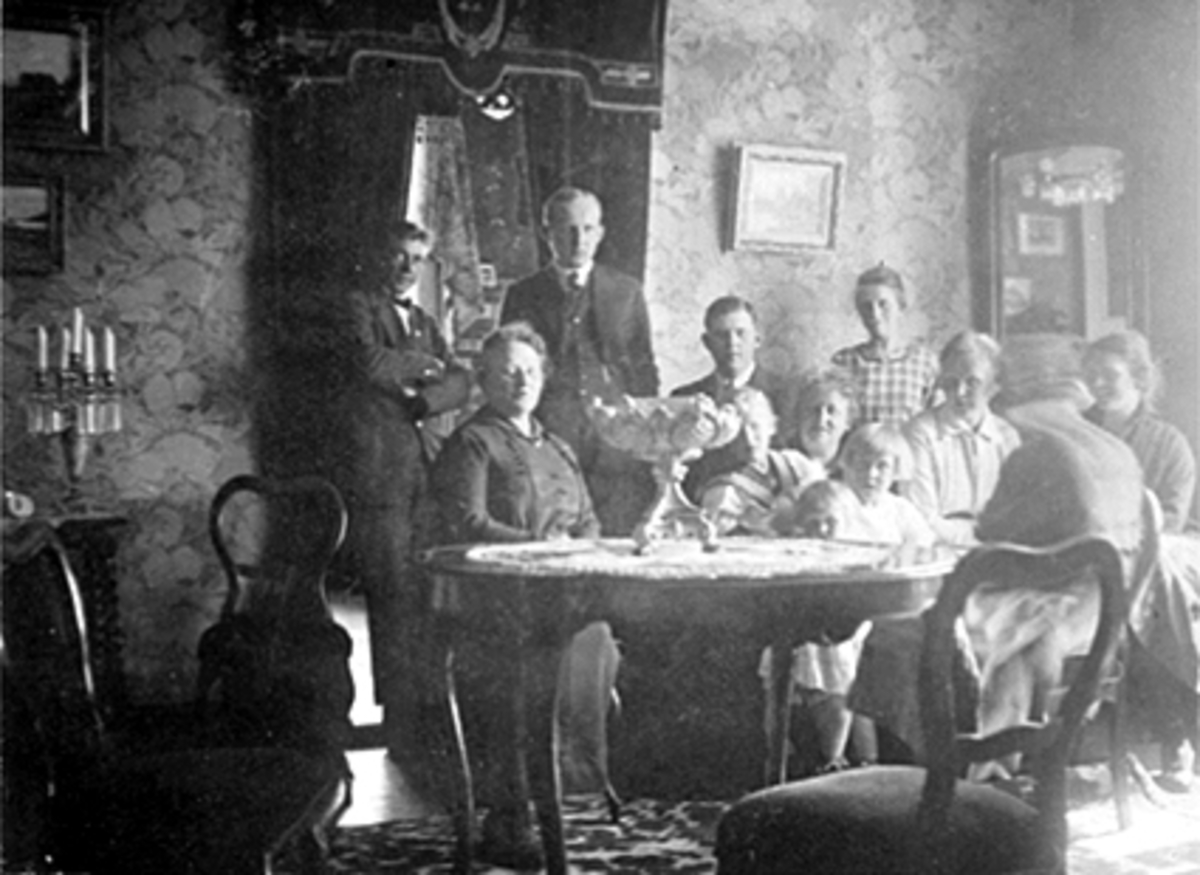 Anno Domkirkeodden, INTERIØR STUE, GRUPPE 12, FAMILIEN LØKEN OG FAMILIEN ULVEN, FRA VENSTRE UKJENT, CHRISTEN LØKEN, GUNNAR ULVEN, UKJENT, CHARLOTTE GRÜNER, HANS ARISHOLM, HJØRDIS LØKEN, BIRGITTE ULVEN, VESLA ARISHOLM, ALFHILD LØKEN OG MARGARETHE LØKEN, ARVESENSVEG 31.