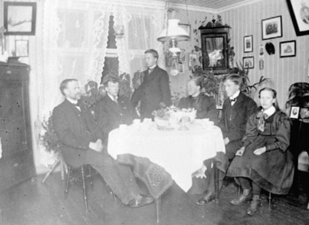 Anno Domkirkeodden, Interiør, laborant Andreas Andersen m/familie. Fra v. Andreas Andersen, Kristian Andersen, stående Lars Andersen, moren Karen fra Jesnes, Johannes Andersen, Anna Andersen. Siste sønn Alfred Andersen var i Amerika. Andreas Andersen jobbet ved Melkefabrikken som smakskontrollør. Se Hamarboka fra 1982…