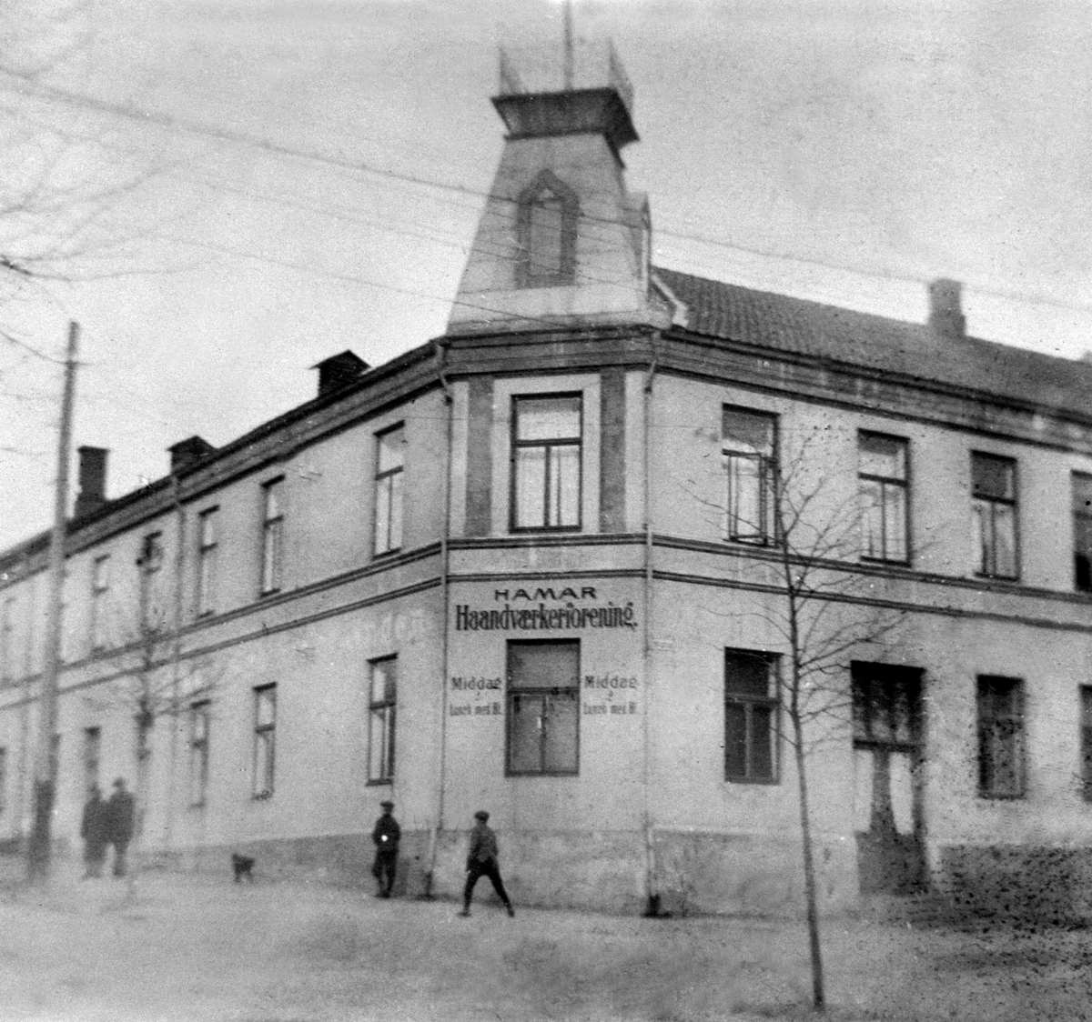 Anno Domkirkeodden, EKSTERIØR, HÅNDVERKERFORENINGEN, FOLKForan huset hvor Østby bodde fra 1914 da han kom til Hamar fraLillestrøm. Han var bokholder og bibliotekar. Malt på fasaden: Hamar Håndverkerforening, Middag & Lunch medØl.