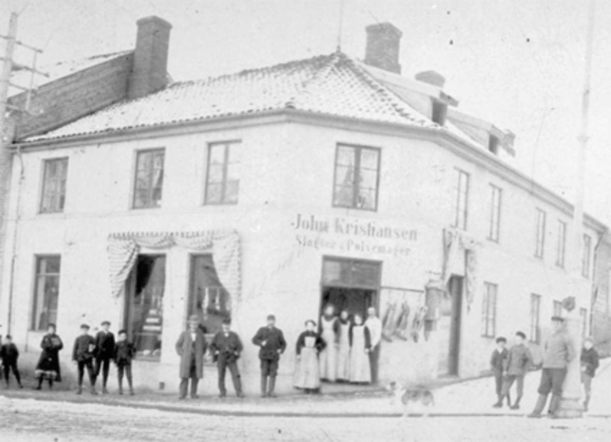 Anno Domkirkeodden, EKSTERIØR, JØNSRUDGÅRDEN, PØLSEMAKER KRISTIANSENS BUTIKK, GRISESLAKT. PØLSEMAKER KRISTIANSEN, JOHN BEGYNTE HER 1878. KJØPTE GÅRDEN 1897. GRISESLAKT HENGER UTENFOR BUTIKKEN. BILDET SENDT SOM JULEKORT TIL SIGNE FRA INGEBORG OG MARIE.
