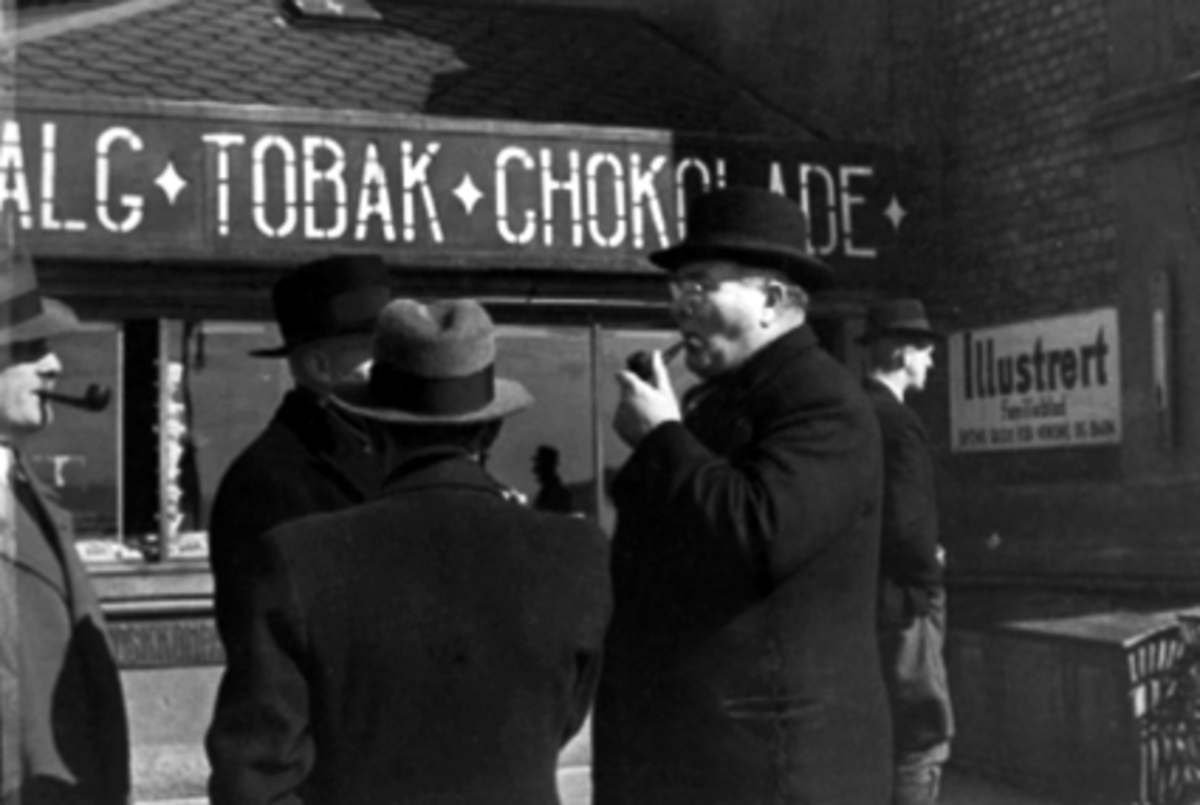 Normann Fotoatelier, Statsminister Nygaardsvold med pipe, 9. april 1940. Venter på kongefamilien på Hamar jernbanestasjon. Daværende ordfører Kristian Bakken står med ryggen til. 2.verdenskrig.