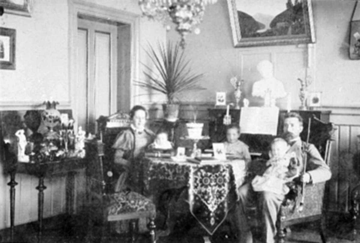 Anno Domkirkeodden, Interiør stue, familiegruppe Godager. Mor, far, Thora og Even Godager, barn f.v. Fridtjof, Astrid, Thorbjørg.