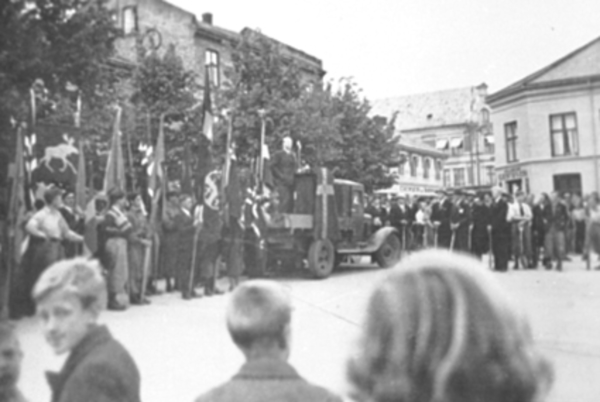 Anno Domkirkeodden, Vidkun Quisling, taler fra lasteplanet av lastebil på Stortorget, Hamar. 1939. Partifeller med flagg, faner, Nasjonal Samling, NS.