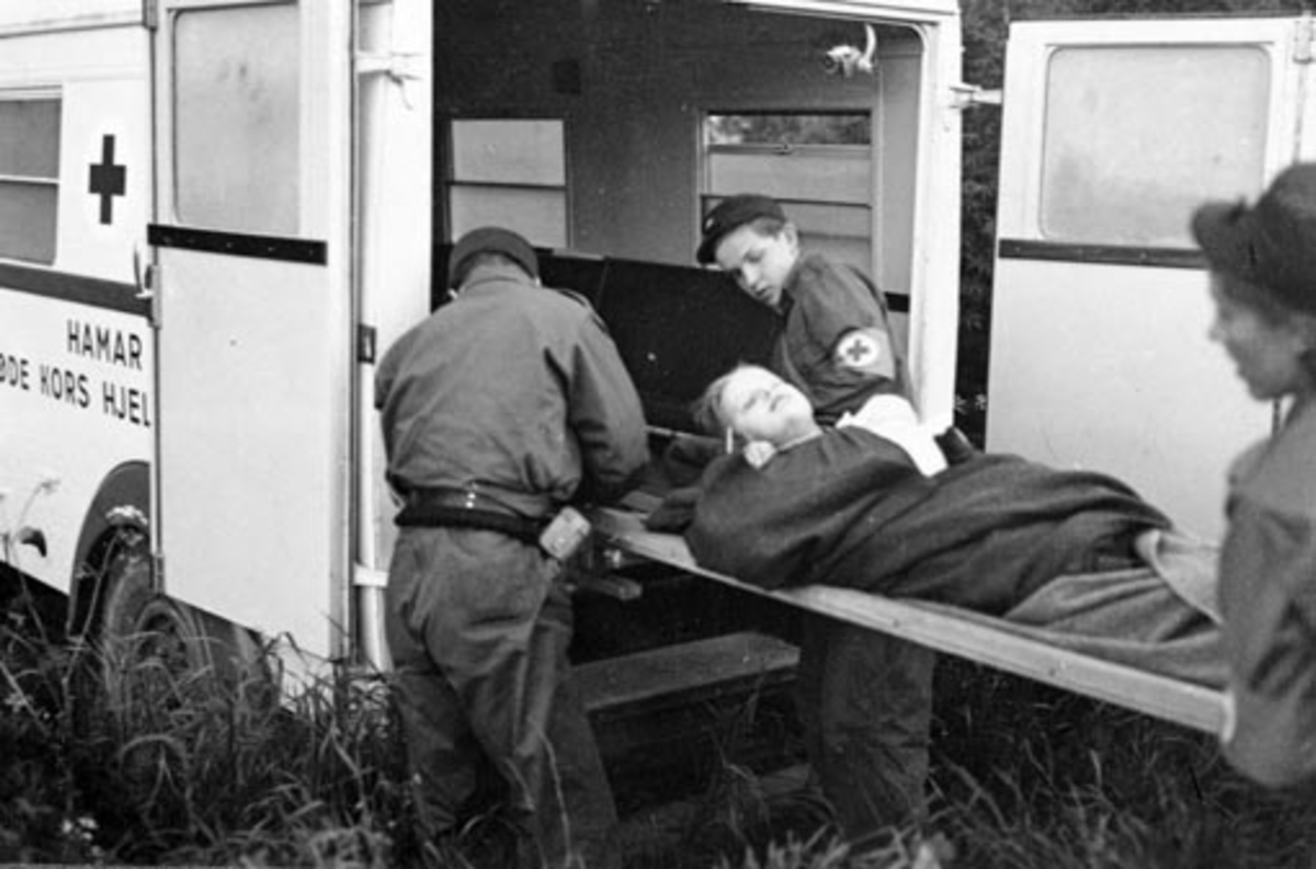Anno Domkirkeodden, HAMAR RØDE KORS HJELPEKORPS. ØVELSE SAMMEN MED NORGES STATSBANER. PASIENT PÅ BÅRE LØFTES INN I AMBULANSE.