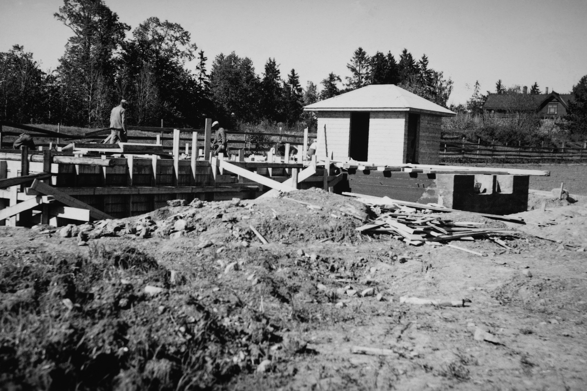 Anno Domkirkeodden, Husbygging i Olav myntmesters gate 54, Hamar. Villa for Fylkeskontorist Reidar Hagen og frue. Funkisvilla tegnet av arkitekt Rolf Prag 1939. Forskalling og muring av kjeller, uthuset med utedo er nesten ferdig, mai /juni 1939. Utgiftene til å reise huset kom på kr. 15000, -