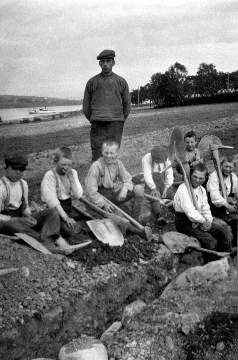 Anno Domkirkeodden, Pause i slitet. Gutter fra Toftes Gave, Nedre Sund, Helgøya graver grøfter. Mjøsbåten D.S. Skreia i bakgrunnen.