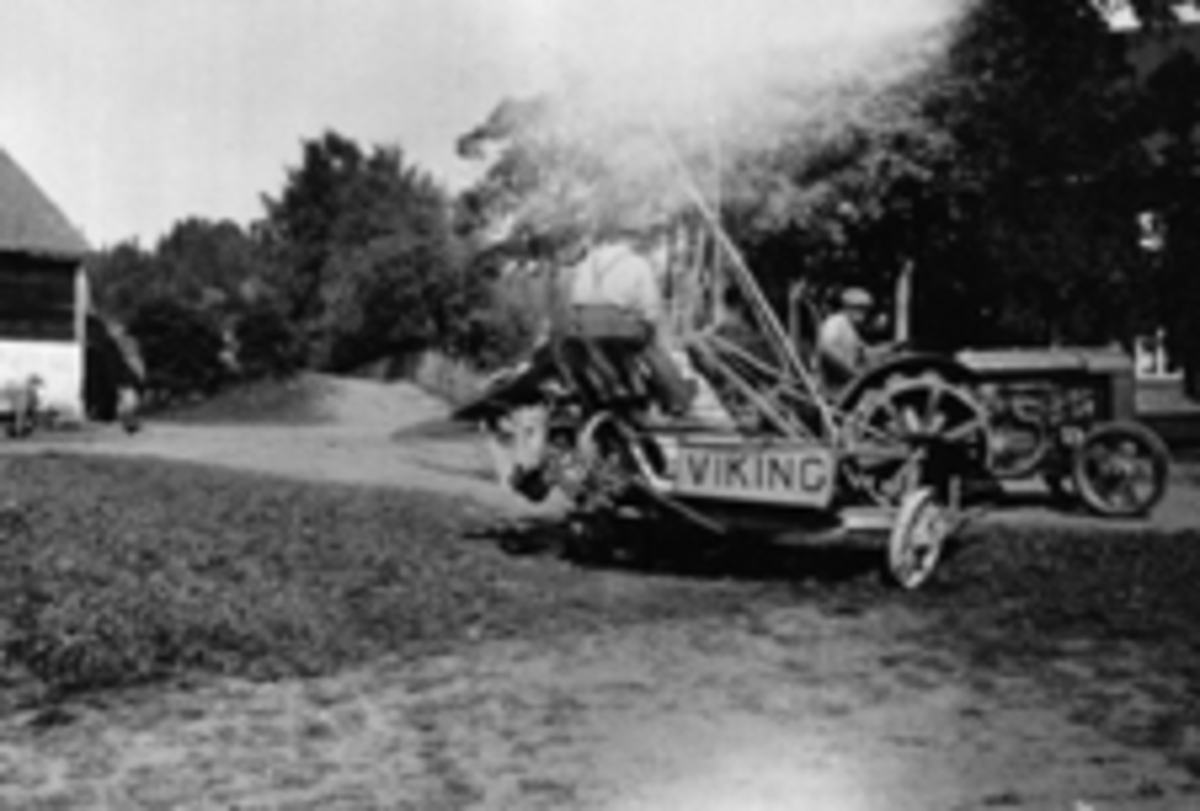 Anno Domkirkeodden, Skuronn på Kirkejordet, Mellem Kise, Nes, Hedmark. Even Arnt Haugen (1909-1962) kjører traktor med Syverim Fagerheim på sjølbinderen "Viking".