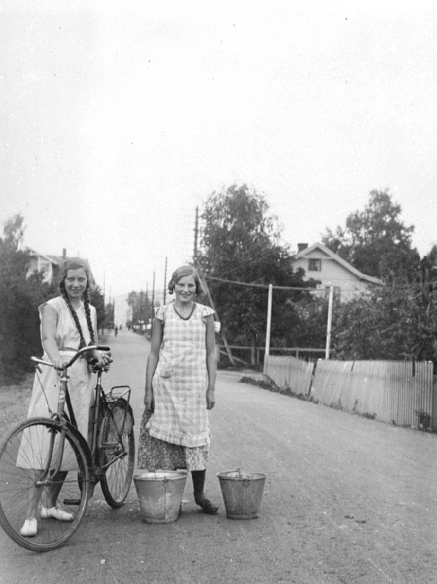 Anno Domkirkeodden, To unge jenter i Storgata, Moelv. Sykkel, sinkbøtter.