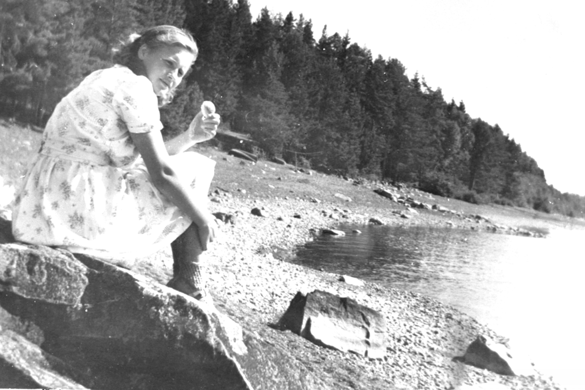 Anno Domkirkeodden, Anna Hatterud f.1931 sitter på stranda ved Furusetstua på Trosterud, Helgøya.