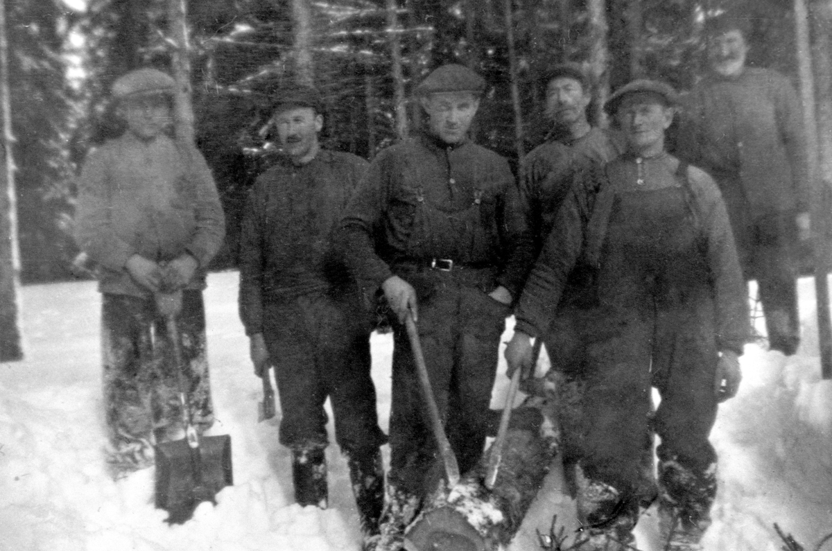 Anno Domkirkeodden, Tømmerhoggere i skogen på Tjerne gård, Ringsaker. Husmenn i arbeid. Olaf Sjørengen, Kristian Sjørengen, Sverre Syversen, Oskar Johansen. Bak er Jon Aspen, Syver Lauritsen.