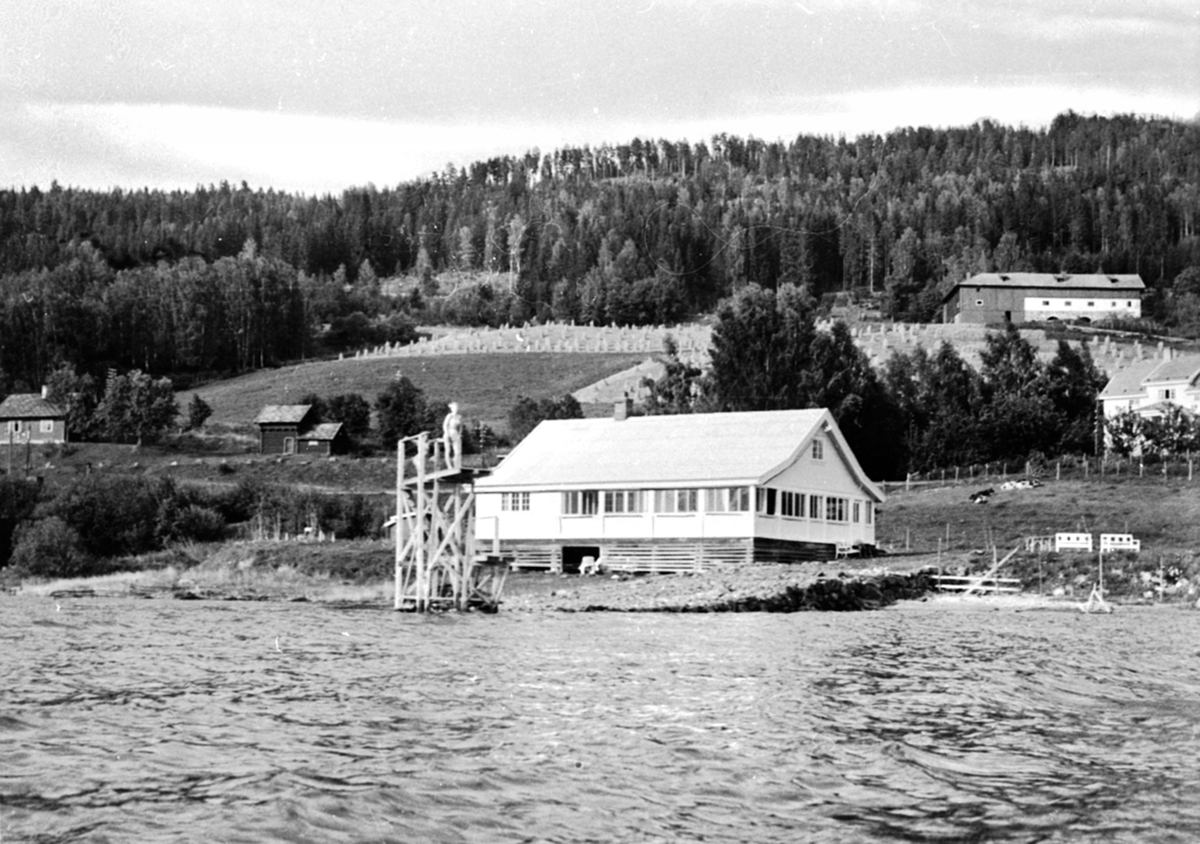Anno Domkirkeodden, Strandhytta på Freng Søndre, Brøttum. Stupetårn. Strandhytta Freng Søndre. Hytta ble revet i 1996 da storflommen i 1995 stod over 1 meter opp på veggen i første etasje. Nåværende Nye Strandhytta ligger nå ca 20 meter lenger sør. Bryggen dere ser i forgrunn i bildet er laget for Skibladner som annlø…