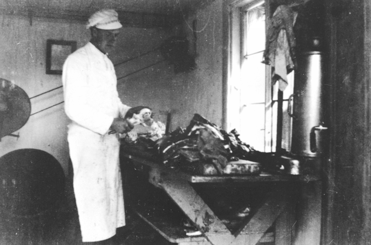 Anno Domkirkeodden, Interiør, slakteri, slakter Ole Pram skjærer kjøtt. Slakter Barflo leide et lite hus bak Framheim kino av fiskehandler Hermansen. Brumunddal.