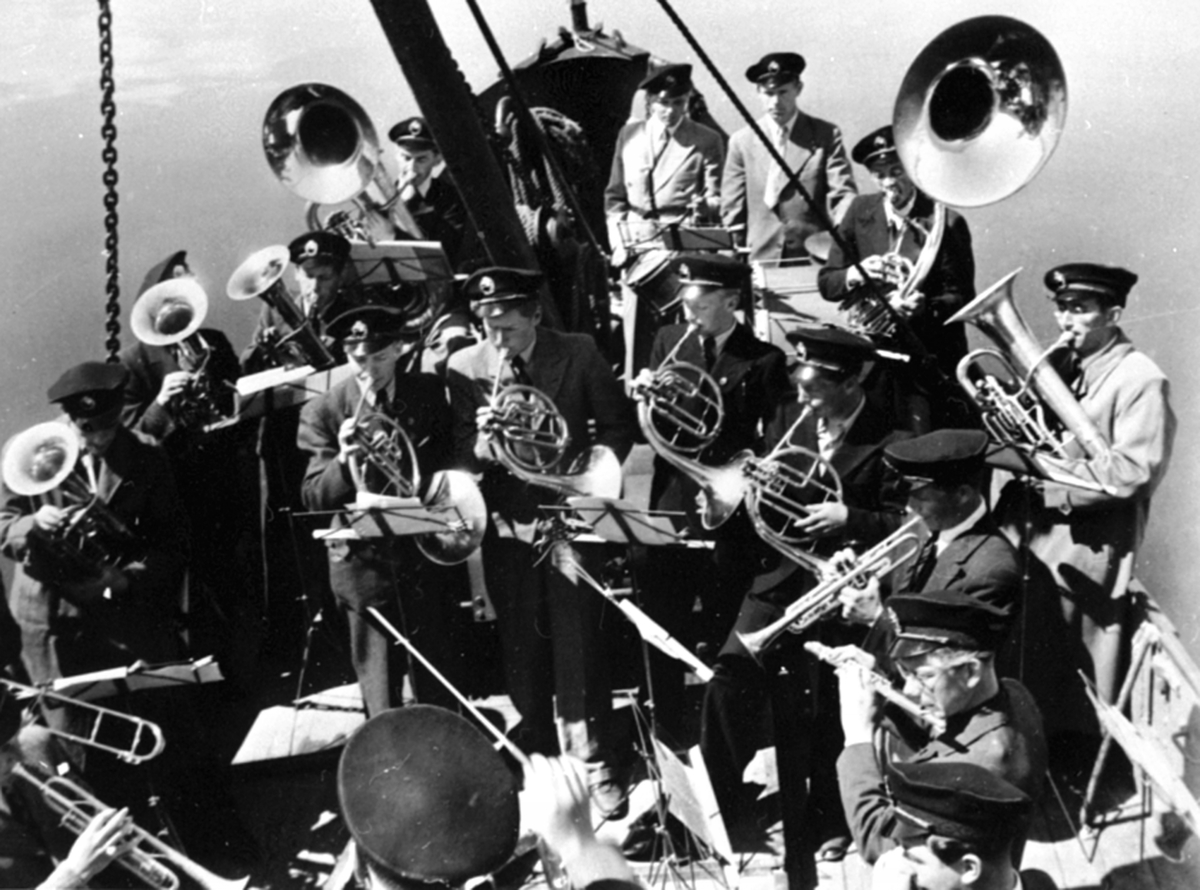 Anno Domkirkeodden, Arbeidere ved A/S Oplandske Konservesfabrikk på båttur med D.S. Hamar. Musikkorps med dirigent Torleif Sangnes ombord. Stabburet, Nora, Brumunddal.