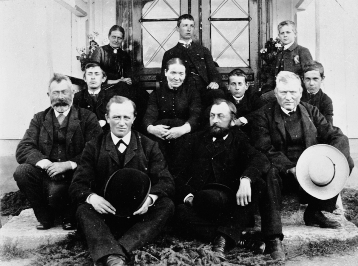 Anno Domkirkeodden, Gruppe på trappa, Buttekvern gard, Brumunddal. Foran fra venstre er Jens Buttekvern, J.M. Narud, Hans Emil Erichsen, ukjent. Guttene er sønner av stiftpprost Erichsen. Bak til venstre er fru Erichsen, i midten husholder til Jens, Karen Torseter.