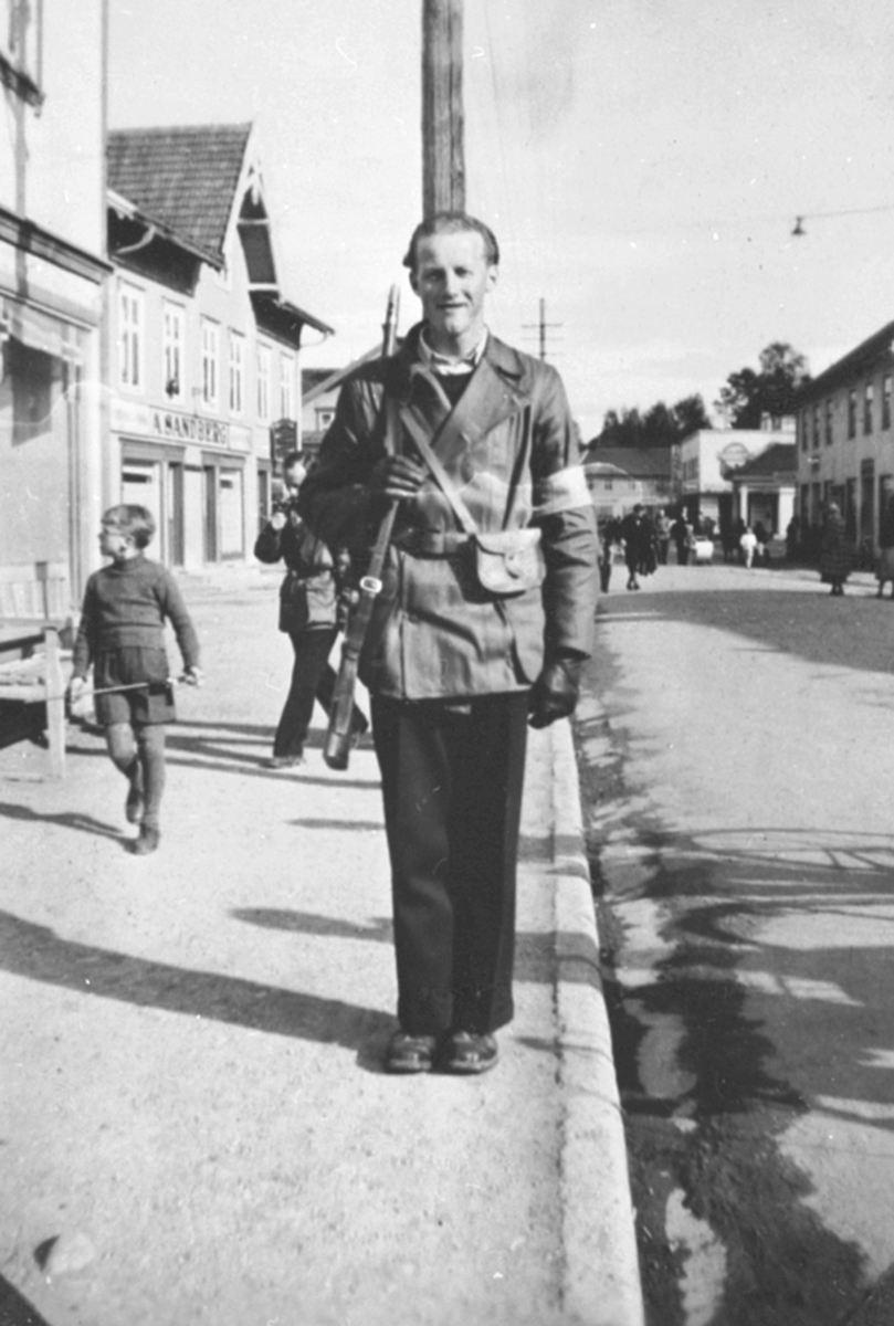 Anno Domkirkeodden, Rørlegger Asbjørn Nordsveen i hjemmefrontutstyr, på vakt langs Furnesvegen, Brumunddal, 17. mai 1945.