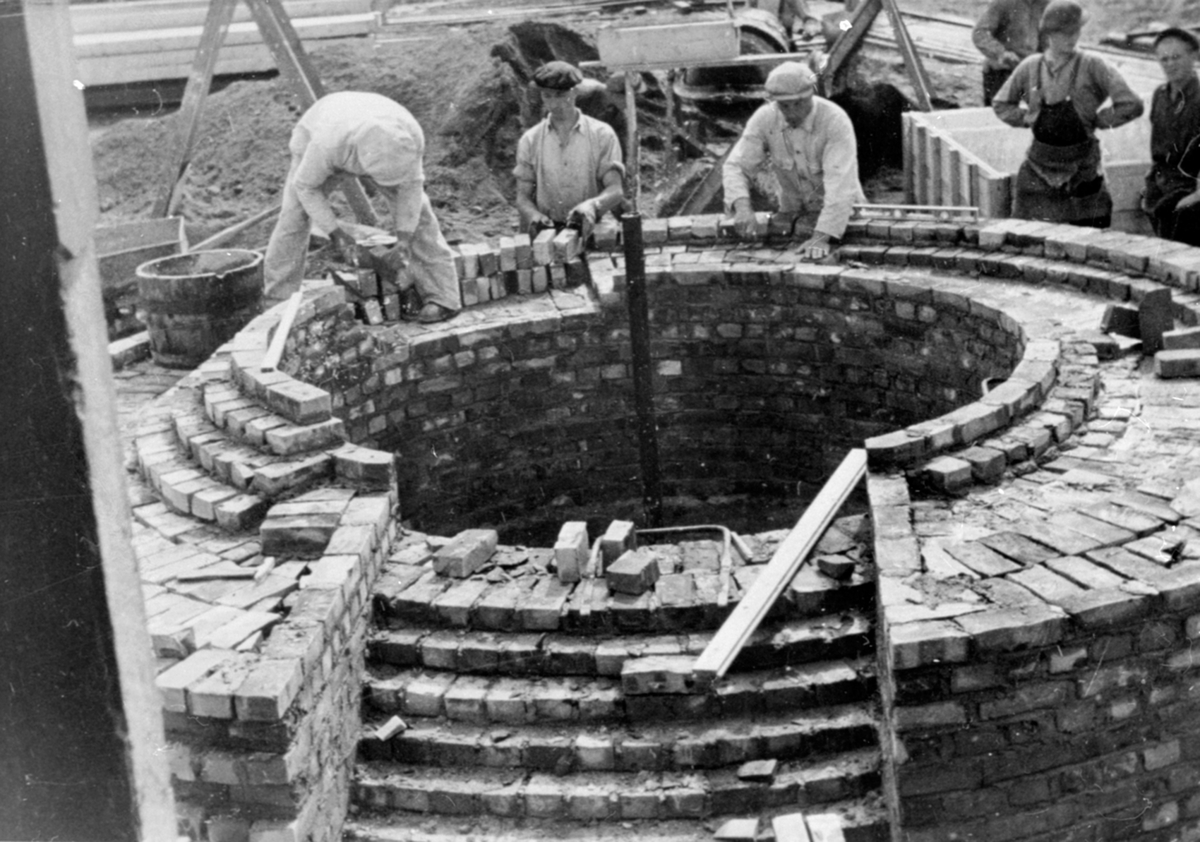 Anno Domkirkeodden, Muring av fundament for fabrikkpipe hos Berger Langmoen A/S, Brumunddal. Murere i arbeid. Murere er Amund Sletten f. 1880 og sønnen Olav Sletten f. 1915.