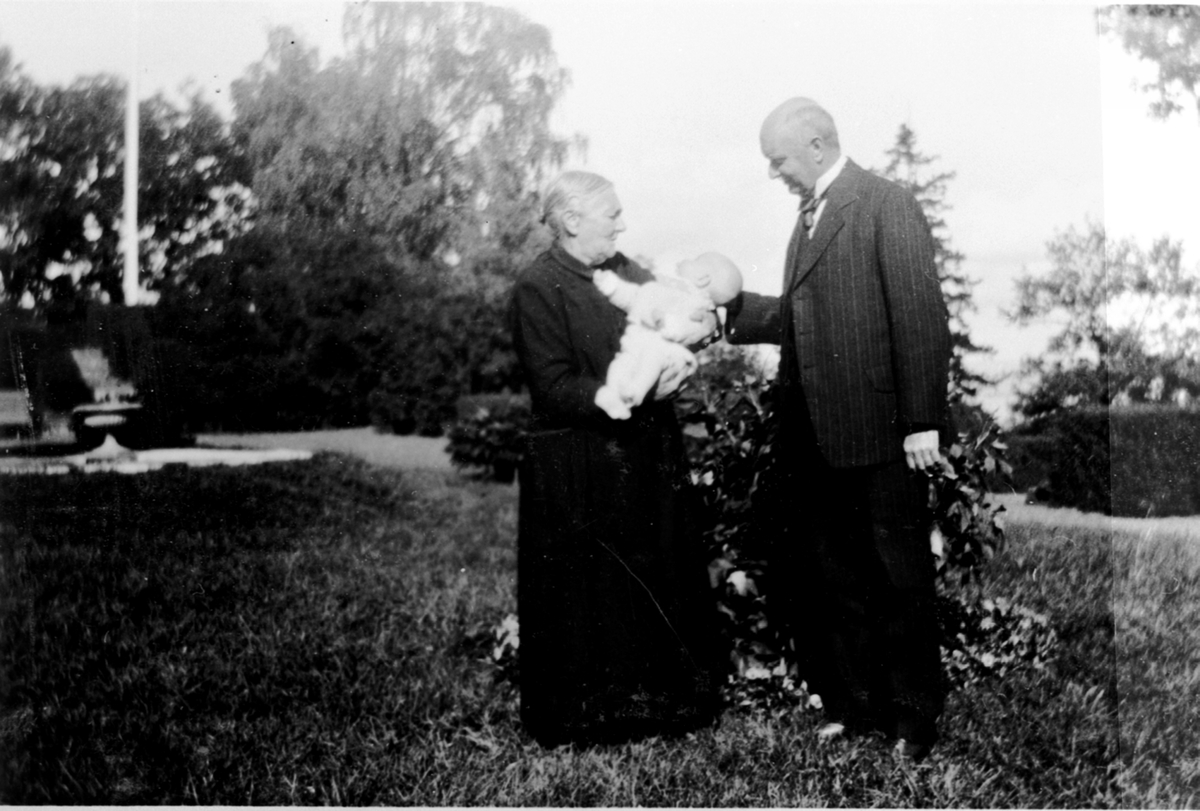 Anno Domkirkeodden, Barnepike Gustine Nilsdatter Sundby f.1859 med Eilert Hoel Forsberg f.1932 på armen. Major Olssøn. I hagen på Hovinsholm, Helgøya.