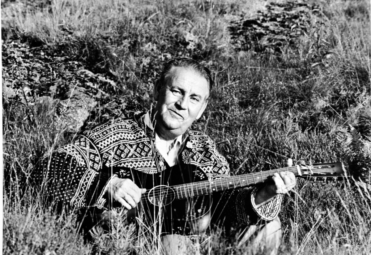 Anno Domkirkeodden, Alf Prøysen sittende med gitaren på fanget ute i gresset.