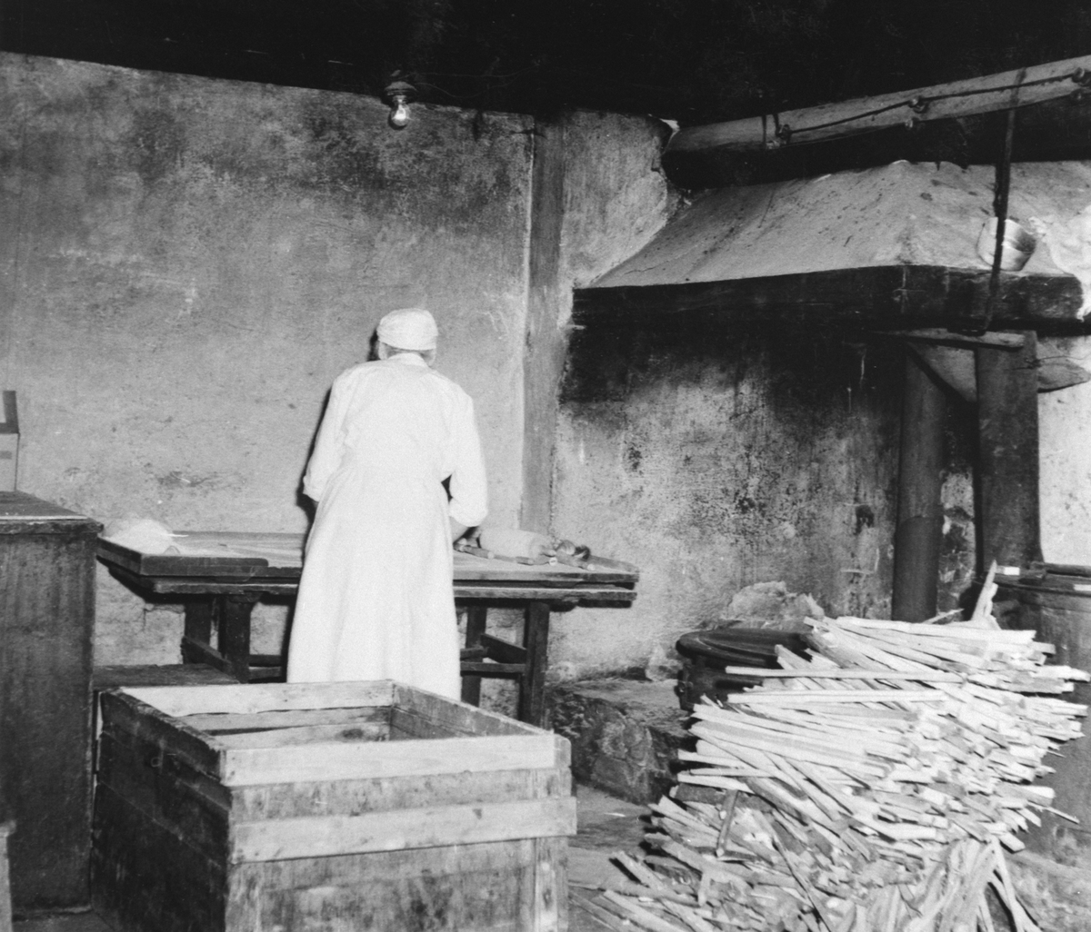 Anno Domkirkeodden, Flatbrødbaking på Tande gård, Ringsaker. Bakerske er Lovise Durendal. Interiør bryggerhus med takke, bakebord og grue.