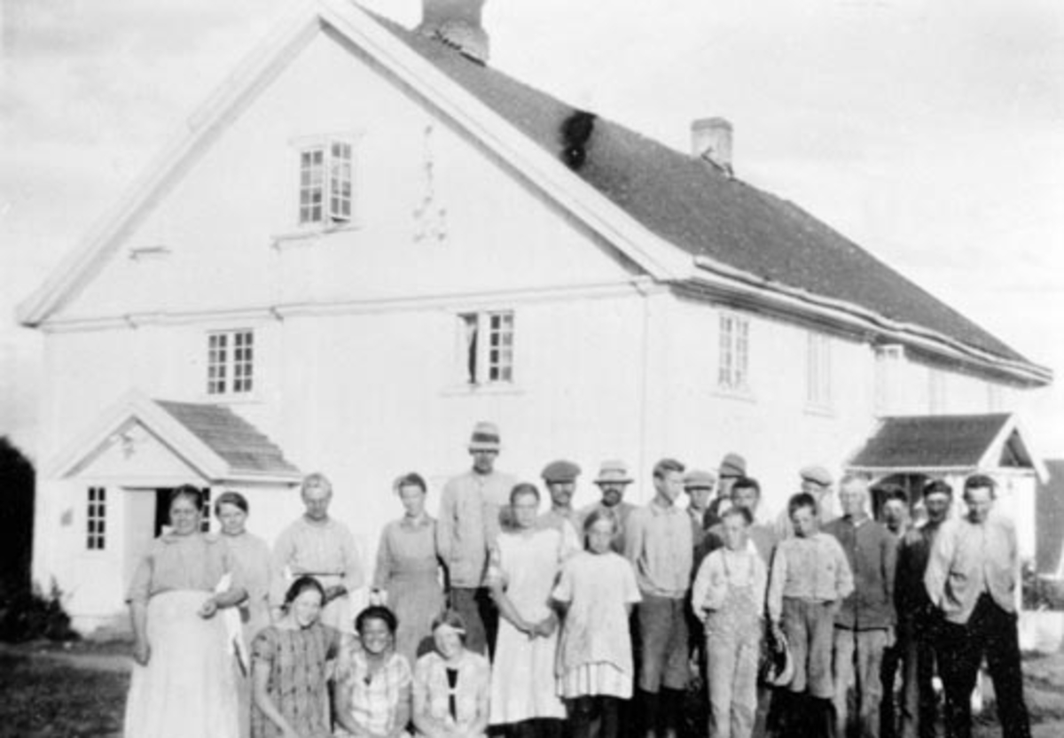Anno Domkirkeodden, Hovedbygningen på Skjelve vestre, Nes, Hedmark. Denne bygningen brant i 1928/29. Stor gruppe arbeidsfolk og sjølfolkutenfor. Ytterst til høyre står Paul Sterud. Nummer fem fra venstre er Kristian Hagen. Av jentene som sitter foran er det Helene Hilstad Ellingsen f.1909 til venstre og Helen Fodstad …