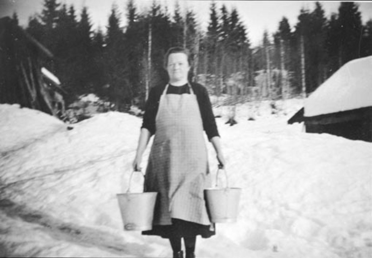 Anno Domkirkeodden, Marthe Haugom (1888-1966) bærer to vannbøtter i Haugom, Stavsjø, Hedmark. Fikk lagt inn vann til hovedbygningen i 1939.