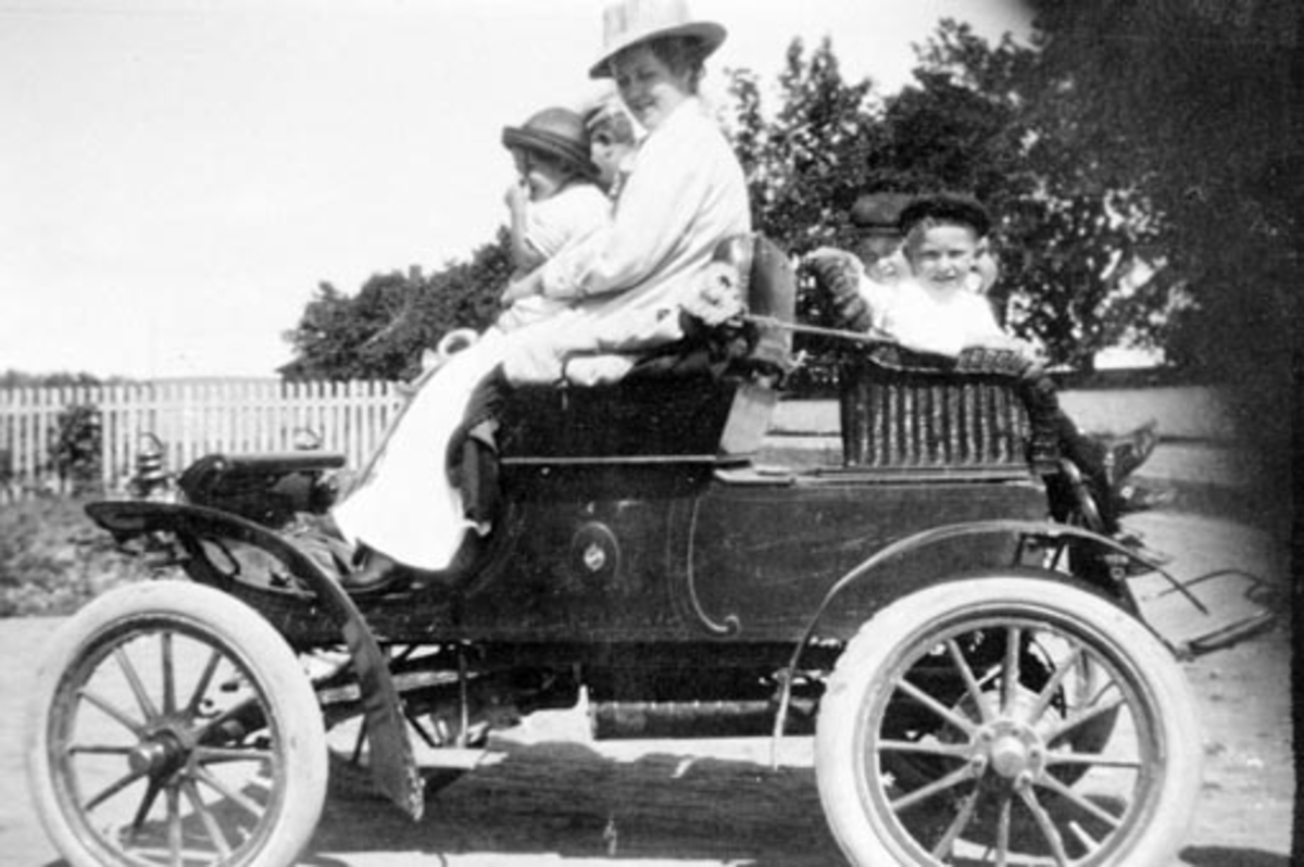 Anno Domkirkeodden, Dyrlege Heggenhaugen med familie. Fru Dagny Heggenhaugen (1883-1931) med barna Jon (f 1904), Trygve (f 1905) og Astrid (f 1907). Gardens første bil, Oldsmobile curved dash, Hilstad Øvre, Stavsjø i Ringsaker. ---- kommentar start ---- Dette er en Oldsmobile 1904. Jeg har en identisk bil, så her er j…
