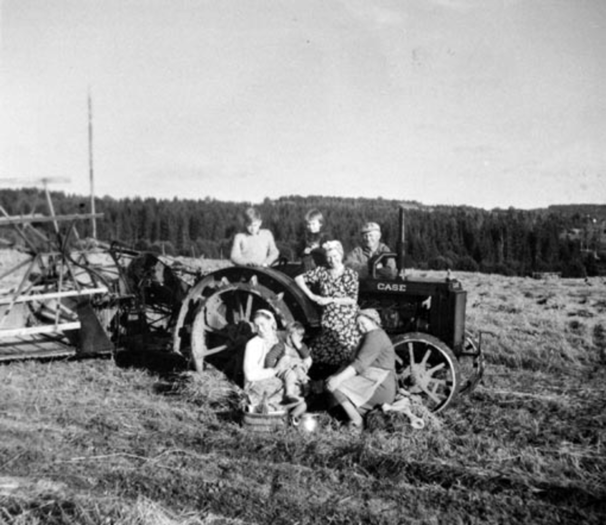 Anno Domkirkeodden, Skuronn på Tangnes nordre, Gaupen, Hedmark. Case jerntraktor 1938 modell. Mc.Cormick selvbinder 1918 modell. Kristen Kolstad (1897-1967) bak traktoren. Berit Kolstad (1897-1964) foran til høyre serverer kaffe.