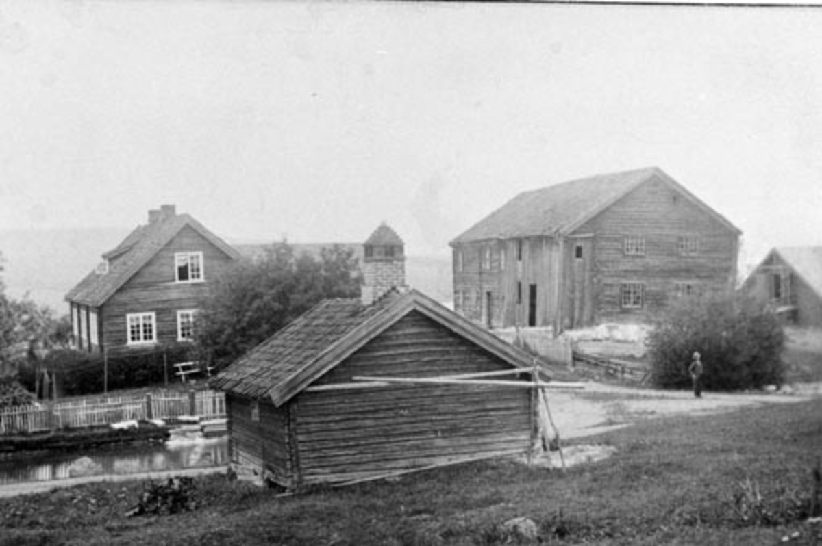 Anno Domkirkeodden, Heggen, Helgøya. Hovedbygning, føderådsbygning, fjøslåven og smia i forgrunn. Dam med ender omtrent der bygdevegen går i dag.
