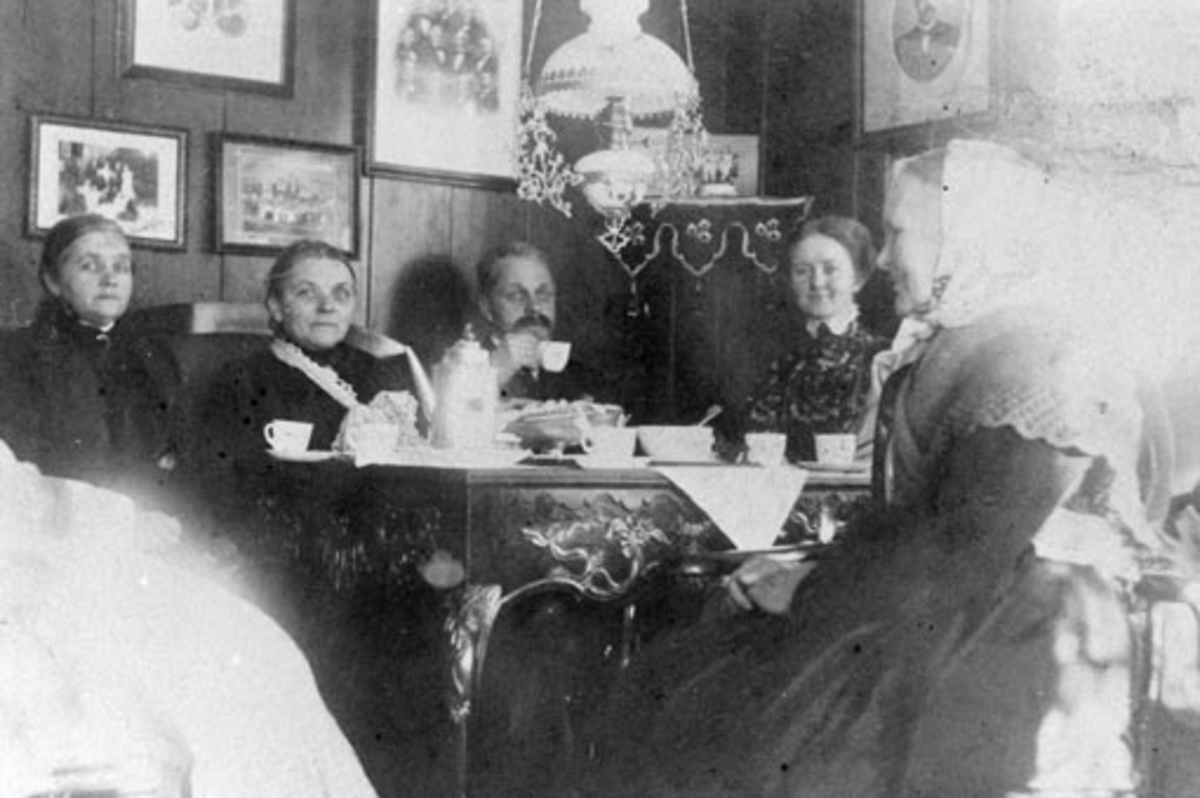 Anno Domkirkeodden, Interiør, stue, Ousdal nordre, Nes, Hedmark. Dekket kaffebord. Til høyre er Hanna Ousdal f.1856. Til venstre er Berte Ousdal f.1828. Gjesten er ukjent.