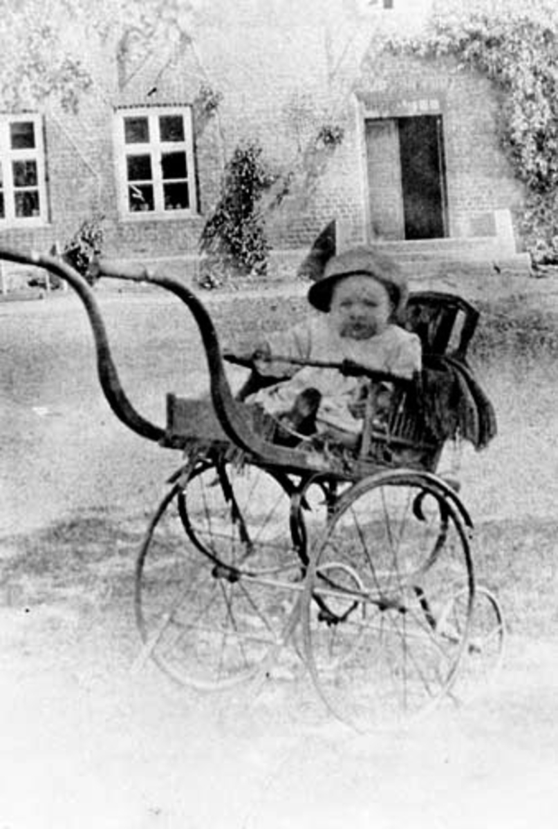 Anno Domkirkeodden, Liten gutt i barnevogn med to store og et lite hjul. Muligens Even Arnt Haugen f. 1909 på Mellom-Kise, Nes, Hedmark.