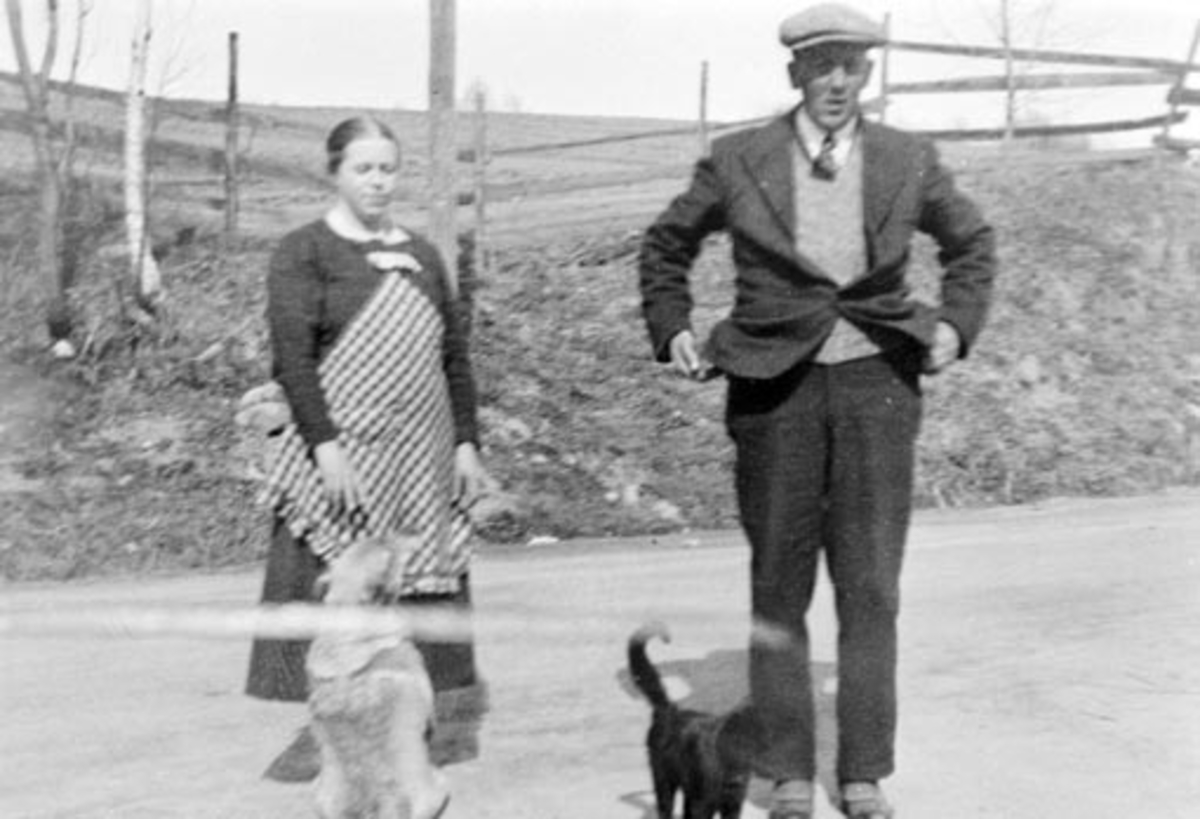 Anno Domkirkeodden, Husholderske og butikkdame Tora Johansen med hund og ekspeditør Jens Evensen Mengshoel (1897-1971) med katt i vegen utenfor landhandleriet Svingen på Mengshoel fergested.