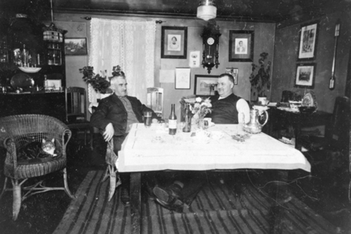 Anno Domkirkeodden, Interiør, stue med skjenk, klokke, bilder på Jesnes øvre, Furnes, Ringsaker. Fra venstre er Kristian Storihle F.1883, Bernt Haave F.1884. To ivrige hestekarer.